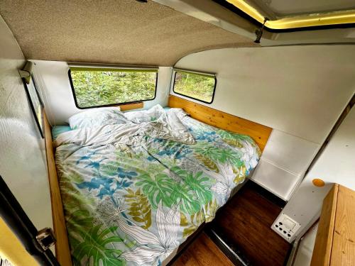 a bed in the back of a trailer with two windows at Auszeit im Wald direkt am See in Schleiz