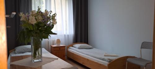 Cette chambre comprend 2 lits et un vase de fleurs sur une table. dans l'établissement Centro Unita, à Cracovie