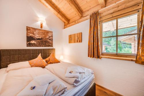 Schlafzimmer mit einem Bett mit weißer Bettwäsche und einem Fenster in der Unterkunft Chalet am Teich in Neukirchen am Großvenediger