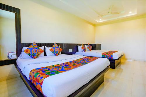 a bedroom with two beds with colorful pillows at FabExpress Vivaanta Palace in Shirdi