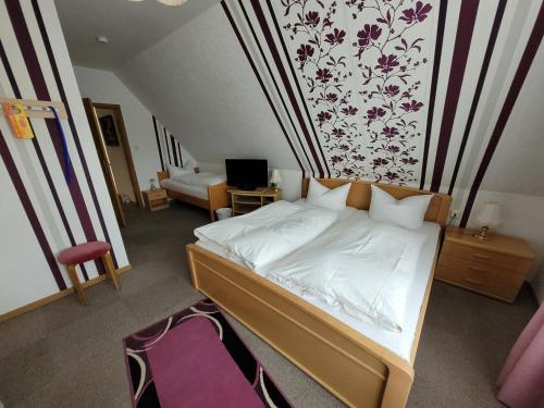 sypialnia z łóżkiem i ścianą z kwiatami w obiekcie Hotel Amselhof w mieście Bispingen