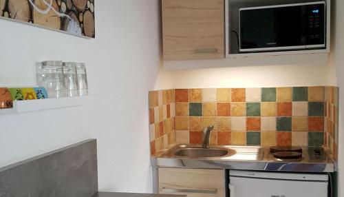 une cuisine avec un évier et un micro-ondes dans l'établissement Studio proche port et plages, piscine, à Hyères