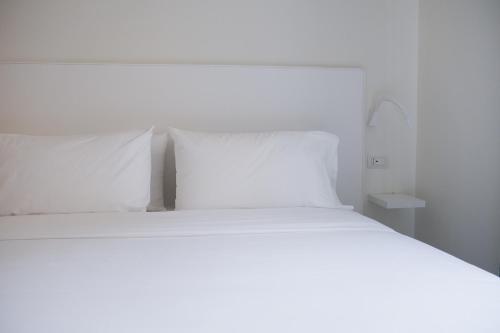 a bed with white sheets and pillows in a room at Supernova in Savona