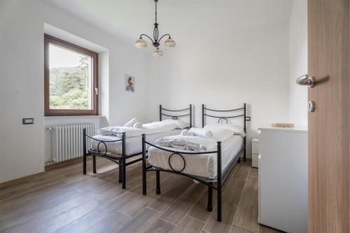 sypialnia z 2 łóżkami, stołem i oknem w obiekcie Casa Stefano w mieście Riva del Garda