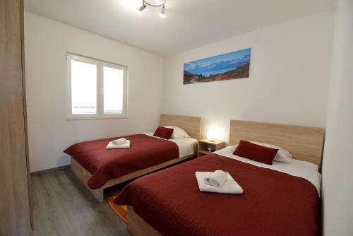 2 Betten in einem kleinen Zimmer mit roter Bettwäsche in der Unterkunft Kuća za odmor Ante in Lišane Ostrovičke