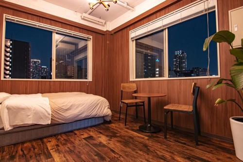 een slaapkamer met een bed en een raam met uitzicht op de skyline van de stad bij HOSTEL CHILLAX in Osaka