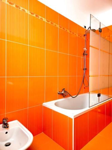 an orange tiled bathroom with a sink and a tub at Maison Andrea in Farra di Soligo
