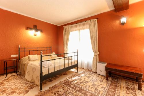 a bedroom with orange walls and a bed and a window at Puchner Kastélyszálló Prémium in Bikal