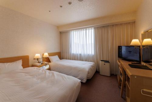a hotel room with two beds and a flat screen tv at Shimonoseki Station West Washington Hotel Plaza in Shimonoseki