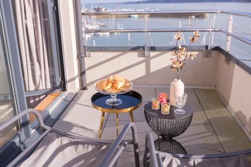 un balcón con una mesa con un plato de comida. en Le Nautica Hôtel en Perros-Guirec