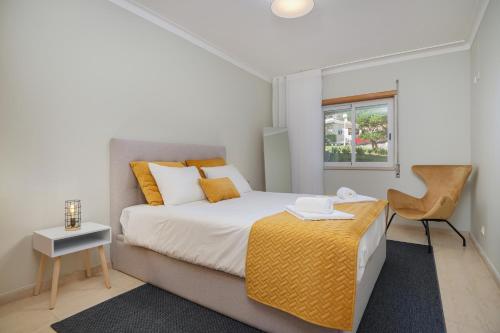 a bedroom with a bed and a chair and a window at Sea Lux Ericeira Beach in Ericeira