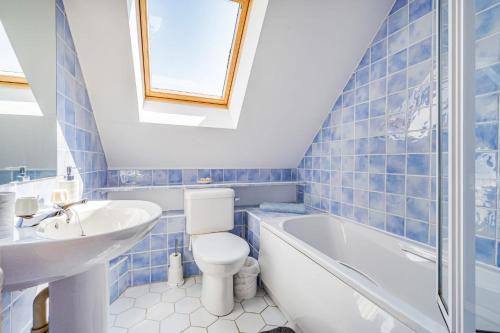 Baño de azulejos azules con aseo y lavamanos en Pebble Paradise Beachfront Family Getaway, en Pevensey
