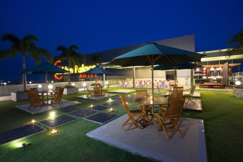 a patio with tables and chairs and umbrellas at night at Golden Palace Hotel Lombok in Mataram