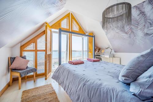 ein Schlafzimmer mit einem Bett und einem großen Fenster in der Unterkunft Pebble Paradise Beachfront Family Getaway in Pevensey