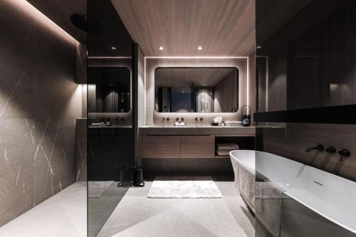 un bagno con vasca, lavandino e specchio di LE CHALET - Luxury Hideaway a Oberlech