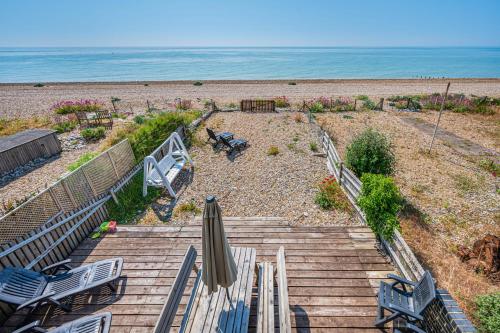 a staircase to the beach with an umbrella and chairs at Pebble Paradise Beachfront Family Getaway in Pevensey