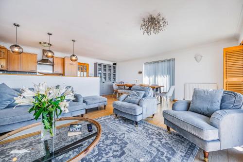 a living room with blue couches and a table at Pebble Paradise Beachfront Family Getaway in Pevensey