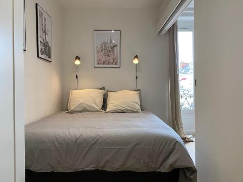 een slaapkamer met een bed met twee lampen en een raam bij Le Paris Appart' T2 au centre du Mans in Le Mans