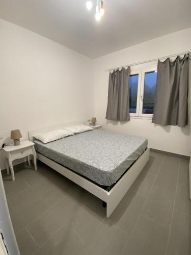 a white bedroom with a bed and a window at Li sireni LA FRISAIA Bilocale vista mare FP7 Trinità d'Agultu e Vignola in Cascabraga