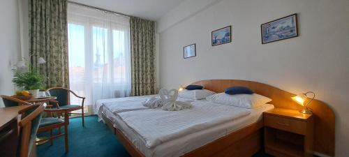 a bedroom with a bed and a desk and a window at Hotel Legie in Prague