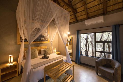 a bedroom with a canopy bed with a window at Lindiwe Safari Lodge in Hoedspruit