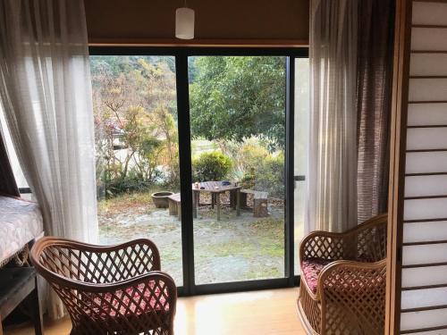 een kamer met 2 stoelen en een glazen schuifdeur bij Yamabitoan - Vacation STAY 04295v in Chikushino