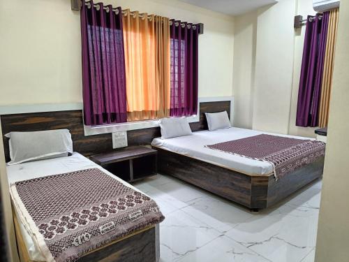 two beds in a room with purple curtains at Hotel Sai viraj palace in Shirdi