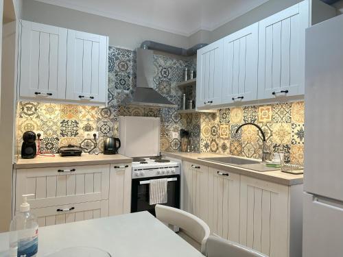 uma cozinha com armários brancos e um forno com placa de fogão em Apartment in the center of Agia Sophia em Tessalônica