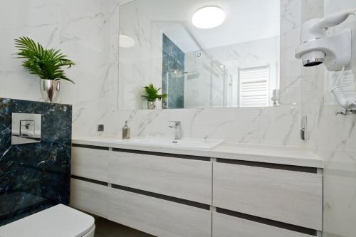 a white bathroom with a sink and a toilet at Pokoje Gościnne IDALIA in Karwia