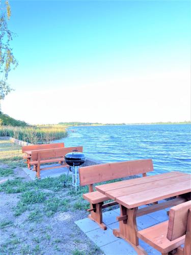 a row of picnic tables and a grill next to the water at Stege Torv Family Apartment in Stege