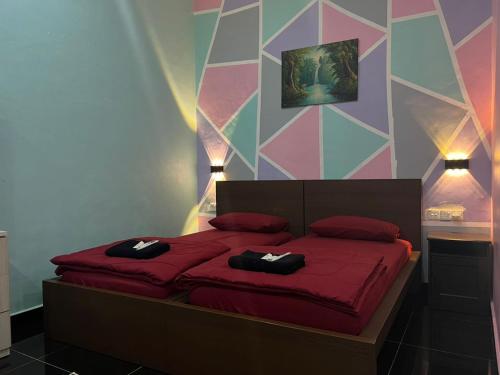 a bedroom with a red bed with a colorful wall at As Sufi Villa in Kampung Sungai Air Tawar