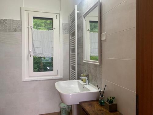 La salle de bains blanche est pourvue d'un lavabo et d'un miroir. dans l'établissement L’Oro di Nonna Adele, à Udine