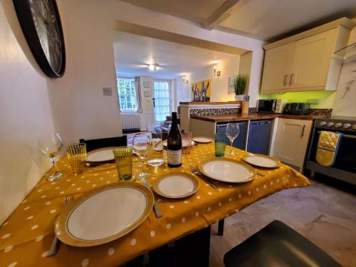 uma cozinha com uma mesa com pratos e copos de vinho em Court Cottage, 2 bed period house em Sarre