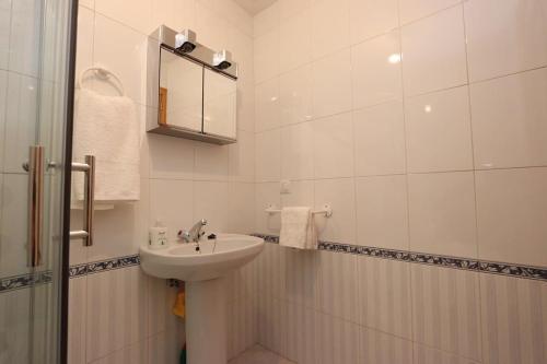 a white bathroom with a sink and a mirror at Apartamento DUQUES DE BÉJAR in Béjar