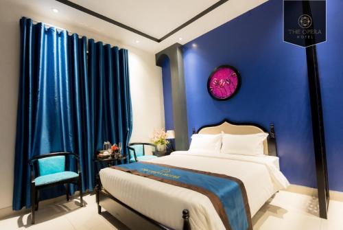 a bedroom with blue walls and a bed and a chair at The Opera Hotel Hải Phòng in Hai Phong