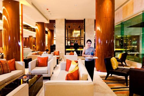 a woman standing in a lobby with a plate of food at Royal Princess Larn Luang - SHA Extra Plus in Bangkok