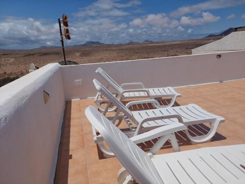 un grupo de sillas blancas sentadas en un balcón en Dunas de Famara, en Famara