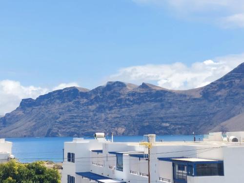 a white building with mountains in the background at Dunas de Famara in Famara
