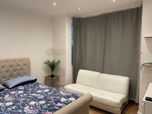 a bedroom with a bed and a couch and a window at Private Room- Direct Travel Central/ Heathrow in London
