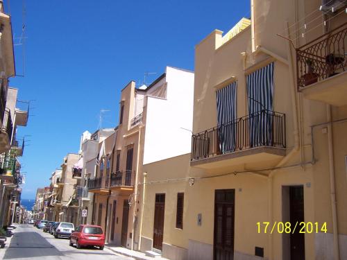 a street with white buildings and a red car at Ni La Za Ciccina in Castellammare del Golfo