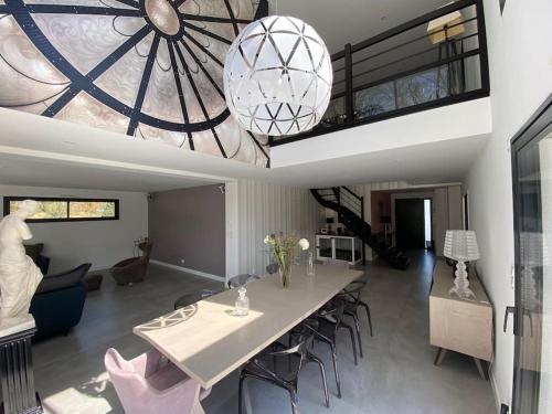 une salle à manger et un salon avec une table et des chaises dans l'établissement Villa avec piscine et spa proche circuit 24H Le Mans, à Changé