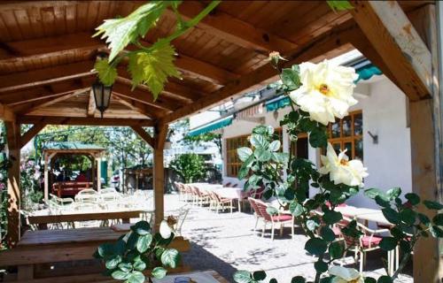 een patio met tafels en stoelen en witte bloemen bij S Kilaći in Mostar
