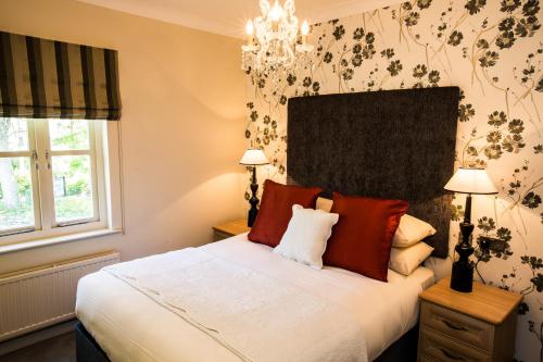 a bedroom with a bed with red pillows and a chandelier at The Broadmead Boutique B&B in Tenby