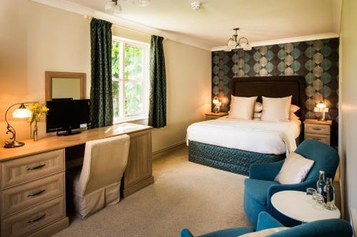a hotel room with a bed and a desk and chairs at The Broadmead Boutique B&B in Tenby