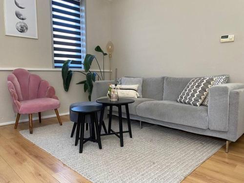 a living room with a gray couch and a pink chair at Guesthouse Katwijk aan Zee in Katwijk aan Zee