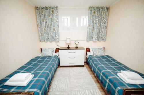 um quarto com duas camas e uma cómoda em TwinHouse Karakol em Karakol