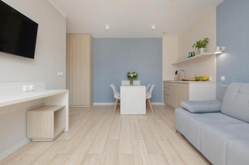 a living room with a white couch and a kitchen at BURSZTYN - BERNSTEIN APARTMENTS in Dąbki