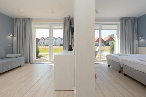 a white bedroom with a bed and a couch at BURSZTYN - BERNSTEIN APARTMENTS in Dąbki