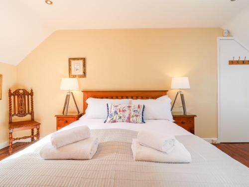 a bedroom with a large white bed with two lamps at 1 The Lane in Chipping Norton