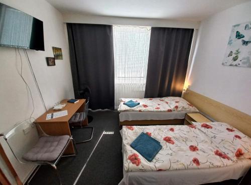 ein Hotelzimmer mit 2 Betten und einem Schreibtisch in der Unterkunft Penzión Šariš in Prešov